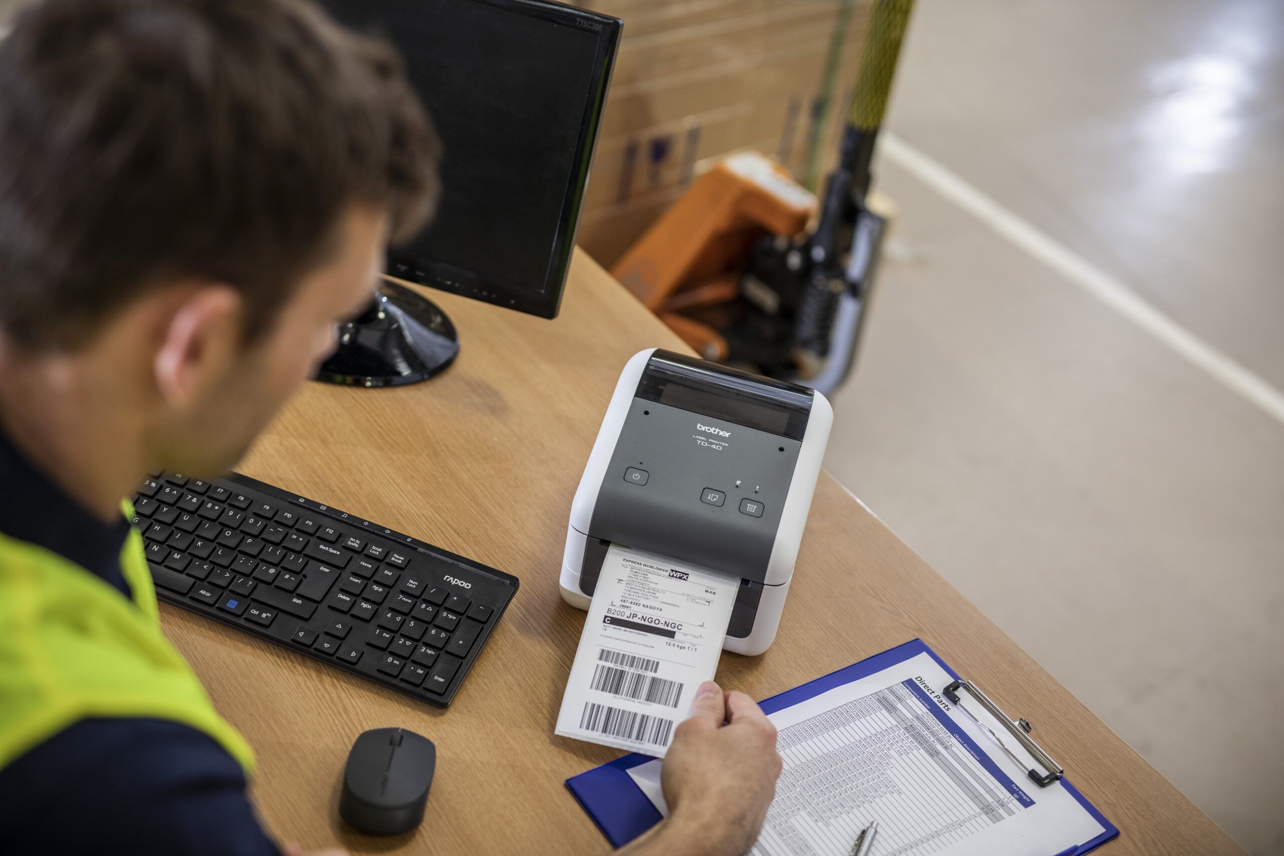 man sitting at desk in warehouse printing a shipping barcode label from a Brother TD 4 direct thermal printer