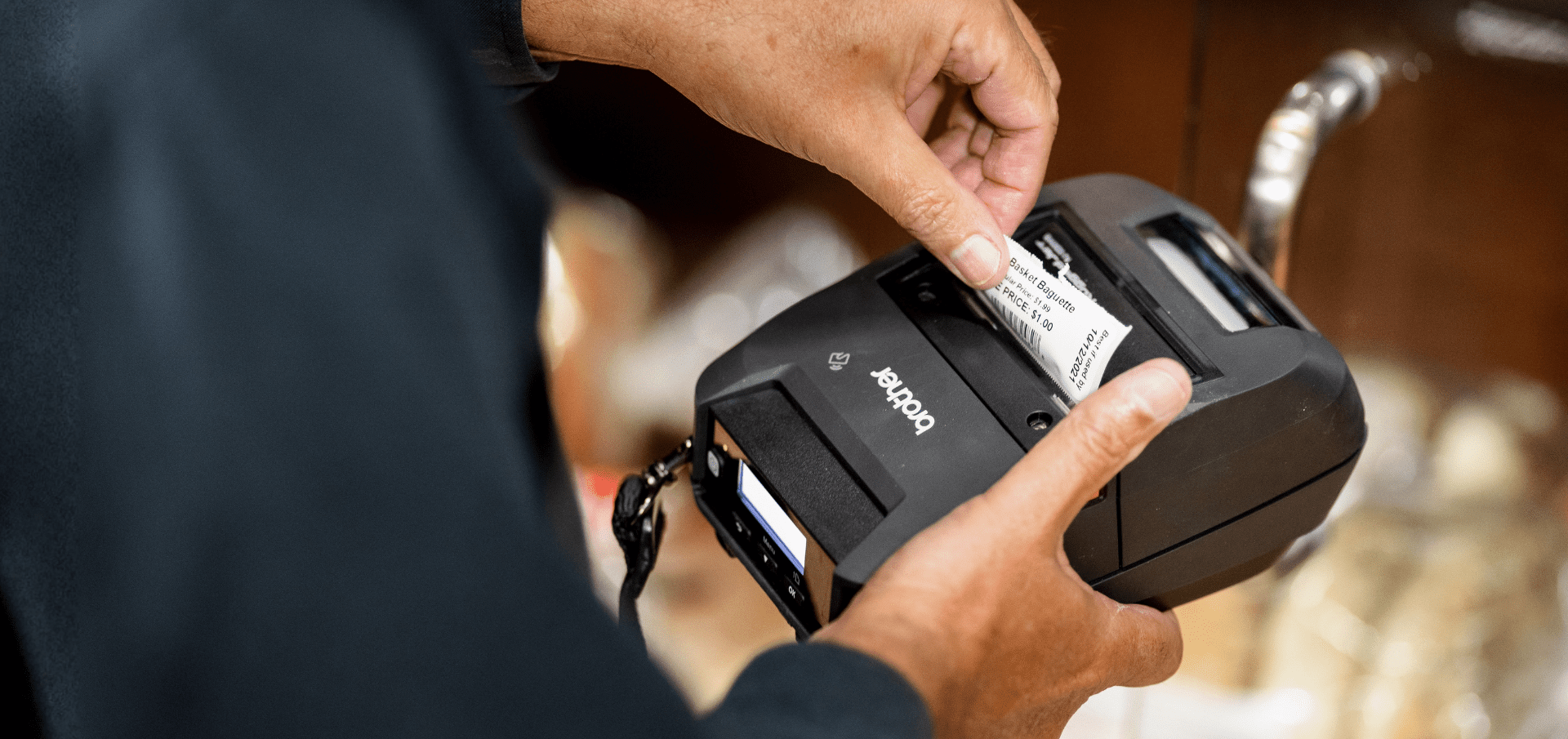 Close-up of hands inserting a label roll into a portable label printer.
